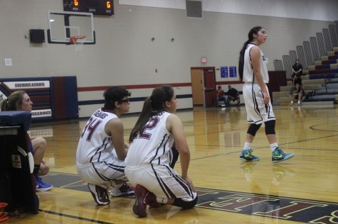 Alina M. (#34) and Bryana H. (#22) waiting to enter the game, while Jane G. (#11) is focused on the action. 